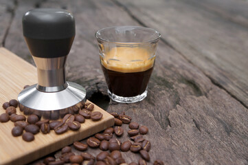 Coffee Espresso and Tamper or coffee press with coffee beans on a wooden table.