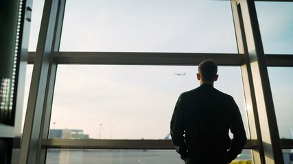 A respectable young man stands at the airport and looks at the plane. Young guy at the airport. The...