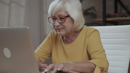 A senior concentrated business lady staring at the screen and lowered her eyeglasses while using laptop