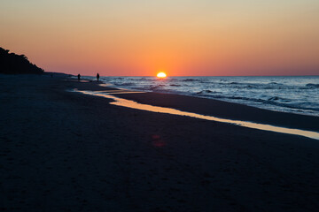 People walking on beach on sunset