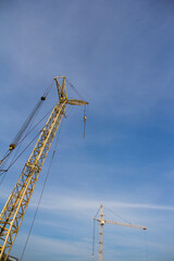Construction crane on a background of blue sky. Equipment for lifting heavy loads on a construction site.