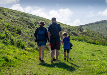 Fototapeta na wymiar The backview of a family walking along the coastal path at Hartland, North Devon..