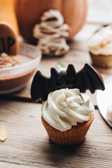 Sweets for halloween party on a wooden table. Halloween style party, candy bar and decorations with pumpkins. Halloween cake, cupcakes and muffins with chocolate. 