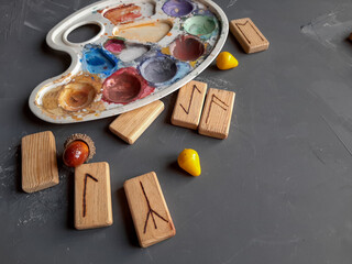 
Runes made of wood on a gray background with a palette for mixing paint