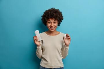 Hygiene protection and womens health concept. Smiling glad Afro American woman holds tampon sanitary napkin demonstrates absorbents for critical days. Happy young female with intimate products