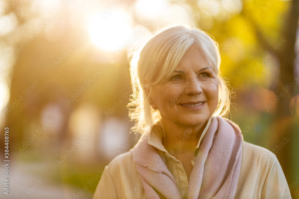 Wall mural senior woman enjoying autumn colors at sunset