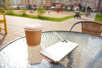 Cup of coffee in the city with a phone