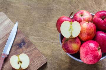 Fresh red apples for Breakfast lie in a bowl with a cut slice on a wooden background