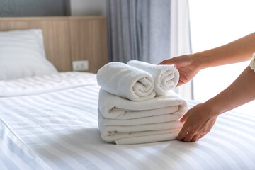 Close up of white hotel bed sheets and towel set , maid cleaning bed. Room service. Hotel business concept.
