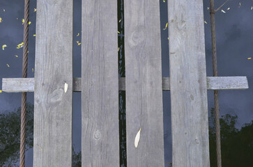 Fototapeta premium Wooden thresholds on the background of a dark river. Beautiful background of wildlife and boards in autumn.