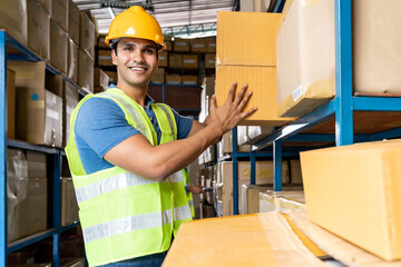 Indian warehouse worker put cardboard box in shelf