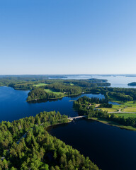 Aerial view on the bridge over the lake. Blue lakes, islands and green forests from above on a sunny summer morning. Lake landscape in Finland, Paijanne.