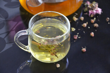 A mug with tea. Dry flowers. Tincture on plants. Delicious drink.