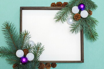 Christmas composition of fir branches, pine cones, Christmas toys and decorations. Christmas frame with space for text on a light green background