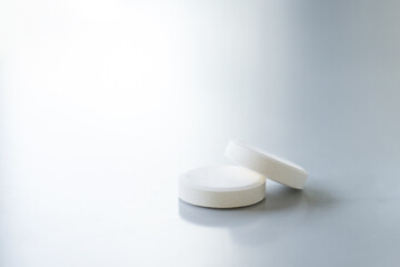 Two white pills on a white table with copy space