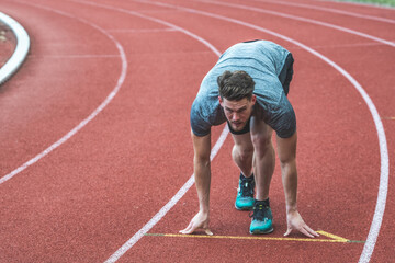 Young Caucasian man standing in start position for run