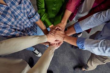 Top view of different ethnicity business people doing fists bump, celebrating success while standing in the office