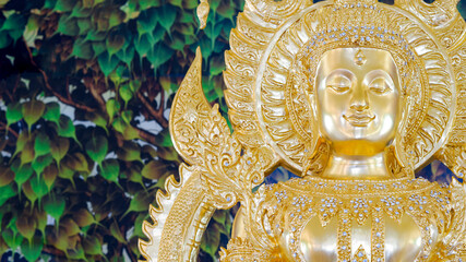 Close up beautiful Thai traditional golden Buddha statue with blurred mural painting on temple wall background
