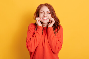Smiling happy beautiful lady pinching her cheeks, looking smiling directly at camera and winking,...