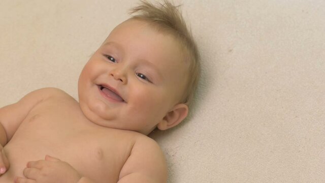 Happy, laughing baby boy lying on bed