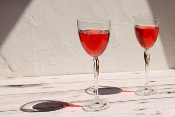 Rose wine on a light background in tall glass glasses with hard light side view