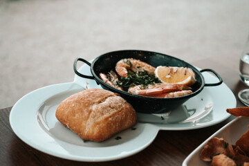 Delicious dish with fried shrimp and lemon in cast iron bowl. Side plate with bread on the side. Lagos, Algarve, Portugal