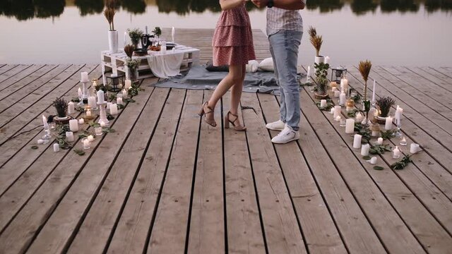 Detail with the feet of a couple in love, while rotating on a deck. Bridge arranged with decoration for marriage requests. Marriage proposal concept. Romantic couple. Slow video.