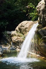 small clean waterfall falls from a rocky ledge in a mountain valley