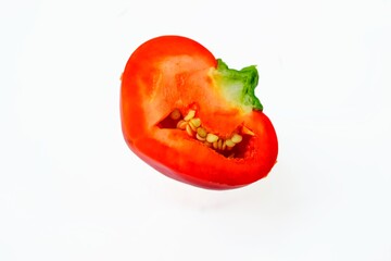 Red fresh pepper cut into half on a white background.