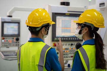 Male and female engineers discuss operating process on machine screen.