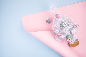 Trend minimalistic modern Christmas banner with white upcycling fir tree with balls on pink and blue background. Minimal festive Christmas flat lay background