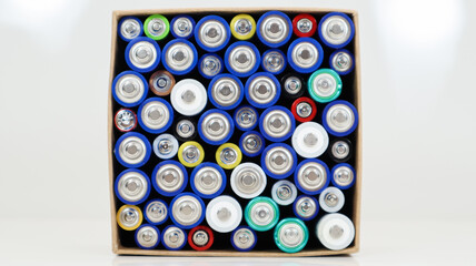 Top view of the background of AAA AA batteries and rechargeable batteries. Choice of batteries. Energy supply and recycling concept. Textures of electric elements packed close together in a box.