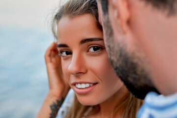 Close-up image of attractive Caucasian woman in the arms of her husband or boyfriend, romantically spending time on the seashore. A loving couple on vacation.