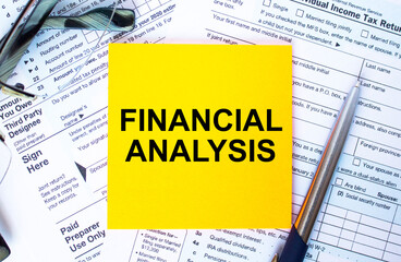 Text Financial Analysis on note paper with the U.S IRS 1040 form,pen and glasses