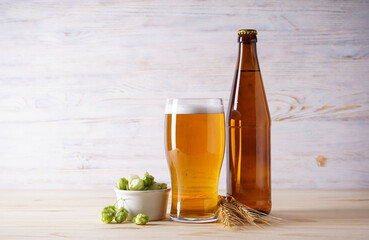 Light beer and hops on wooden background.