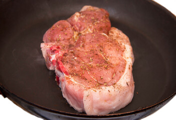 Fresh raw pork steak with spices roasting on frying pan