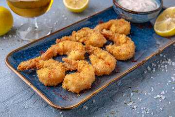 Deep-fried shrimp in batter. Natural delicious food. Greek cuisine menu. Still life in a marine style on a blue background.