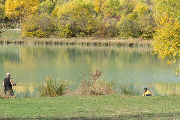 Autumn around a lake in South France, Trees with autumnal colors. A fisher on the left of the picture, a little girl on the right.