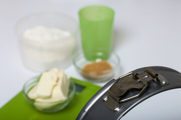 Butter on a kitchen scale. Sugar and flour in containers, collapsible baking dish. Levington cake, stages of preparation.