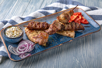 Souvlaki grilled beef and pork on skewers. Natural delicious food. Greek cuisine menu. Still life in a marine style on a blue background.
