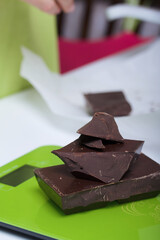 Chocolate on a kitchen scale. Woman breaks a bar of chocolate. Levington cake, stages of preparation.