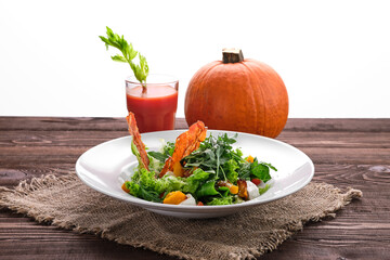 Salad with pumpkin, feta, tomato and crouton with whole pumpkin and tomato juice on background