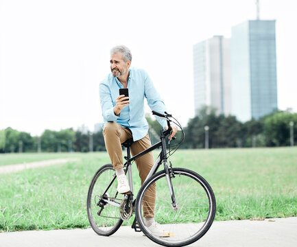 senior man smartphone bicycle cycling cell mobile phone outdoor city park businessman business casual