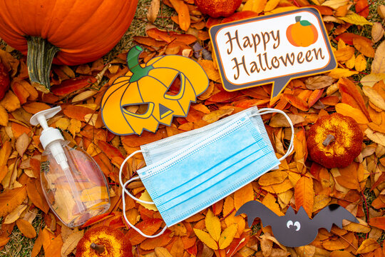 A bottle of a hand sanitizer and facemark with halloween decoration background. Concept: Halloween during a pandemic, covid-19, coronavirus.
