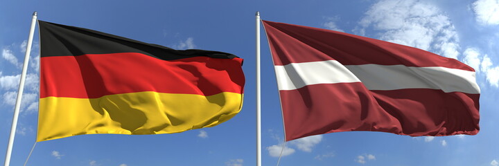 Flags of Germany and Latvia on flagpoles. 3d rendering