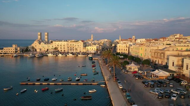 Beautiful panoramic aerial 4K video from flying drone on Molfetta waterfront with the Old Cathedral San Corrado (Duomo Vecchio),port with ships and yachtsand the Molfetta city sunset. Apulia ,Italy