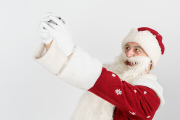 Santa Claus poses, makes a selfie on a mobile phone. Isolated background