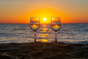 Two glasses of wine on a beach at sunset, Sicily island, Italy