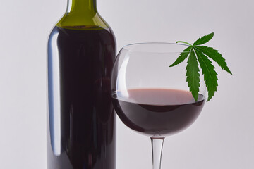 A glass and a bottle of red wine decorated with a hemp leaf