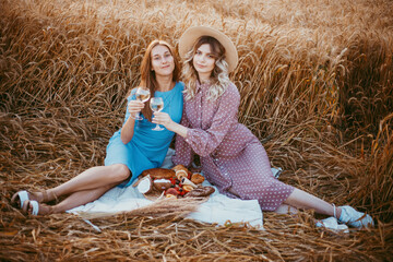 happy friends in a wheat field. girls on a picnic in a field at sunset.